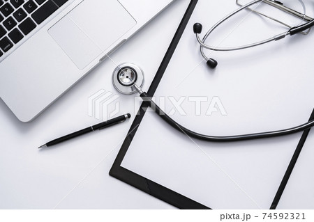 Top view of medical doctor table with stethoscope, clipboard, pen and laptop on white desk Top view of medical doctor table with stethoscope, clipboard, pen and laptop on white desk 74592321