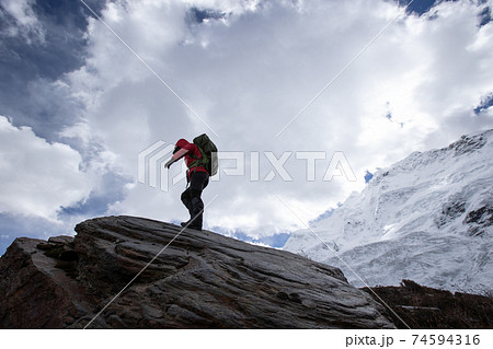 Woman hiker walking on winter mountain top cliff edge 74594316