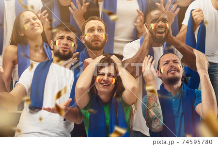 Belgian football, soccer fans cheering their team with a blue scarfs at stadium. Excited fans cheering a goal, supporting favourite players Belgian football, soccer fans cheering their team with a blue scarfs at stadium. Excited fans cheering a goal, supporting favourite players 74595780