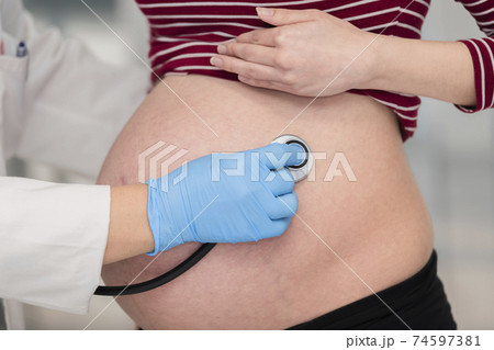 Doctor checking a pregnant woman with a stethoscope 74597381