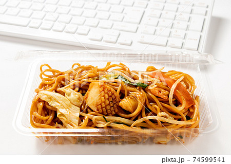 パソコン前でテイクアウトランチイメージ。(プラ容器入りの海鮮醤油焼きそばとキーボード。) パソコン前でテイクアウトランチイメージ。(プラ容器入りの海鮮醤油焼きそばとキーボード。) 74599541