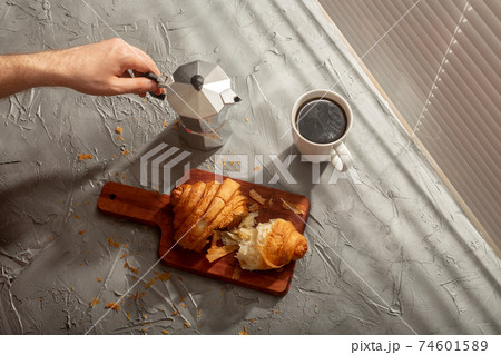 Breakfast with croissant on cutting board and black coffee. Morning meal and breakfast concept. Breakfast with croissant on cutting board and black coffee. Morning meal and breakfast concept. 74601589