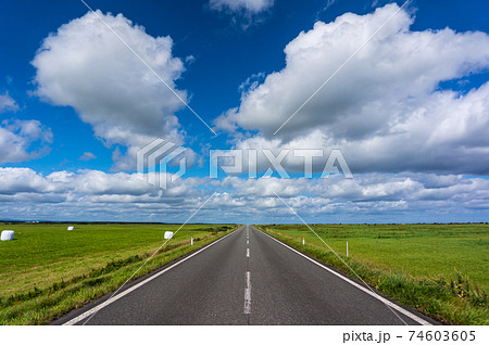 青空の地平線に向かって延びる一直線の開放的な道の写真素材