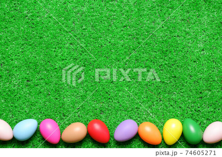 Frame from several multi colored easter eggs on green grass lawn background top view with copy space. Easter holiday banner, card, poster, voucher, invitation template 74605271