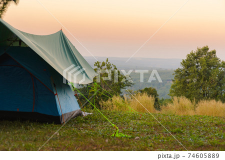 Tourist tent on among meadow in the sunset overlooking mountains. outdoors camping 74605889
