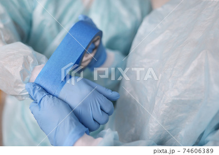 Nurse gluing tape on sleeve of surgical suit closeup Nurse gluing tape on sleeve of surgical suit closeup 74606389