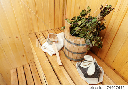 Interior details Finnish sauna steam room with traditional sauna accessories basin birch broom scoop felt hat towel. Traditional old Russian bathhouse SPA Concept. Relax country village bath concept. Interior details Finnish sauna steam room with traditional sauna accessories basin birch broom scoop felt hat towel. Traditional old Russian bathhouse SPA Concept. Relax country village bath concept. 74607652