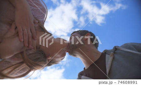 Amorous couple kissing on a background of blue sky. Amorous couple kissing on a background of blue sky. 74608991
