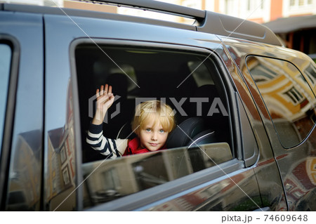 Little boy is waving his hand into the open car window. Greets or says goodbye. Little boy is waving his hand into the open car window. Greets or says goodbye. 74609648