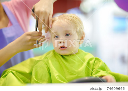 Preschooler boy getting haircut. Children hairdresser with professional tools - comb and scissors. Preschooler boy getting haircut. Children hairdresser with professional tools - comb and scissors. 74609666