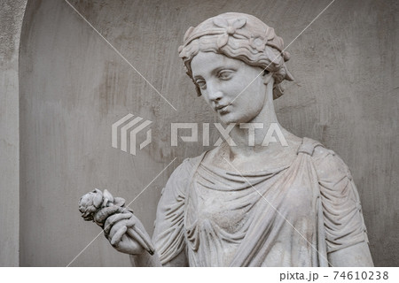 Ancient statue of sensual Greek renaissance era woman with a flower, Potsdam, Germany, details, closeup 74610238