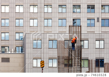 A worker makes installation of a metal frame from steel rods at a construction site. 74610328