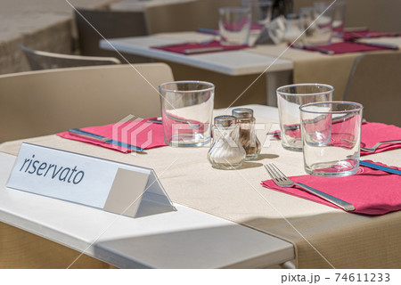 Empty table at street restaurant outdoor ready for visitors with a note saying the table is reserved in Italian language, Italy, summer time 74611233