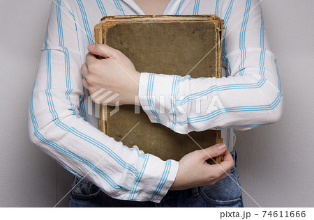 hands of an invisible person holds hugs an old book.  74611666