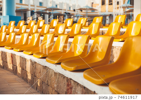 Stone steps with yellow plastic seats. Symbol of closed borders, empty hotels without tourists. Coronavirus COVID-19 quarantine. Hurghada, Egypt. Stone steps with yellow plastic seats. Symbol of closed borders, empty hotels without tourists. Coronavirus COVID-19 quarantine. Hurghada, Egypt. 74611917
