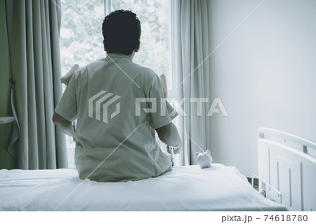 Back view of patient's man leg uses crutches to walk after surgery recovery injury broken bones with pink piggy bank 74618780