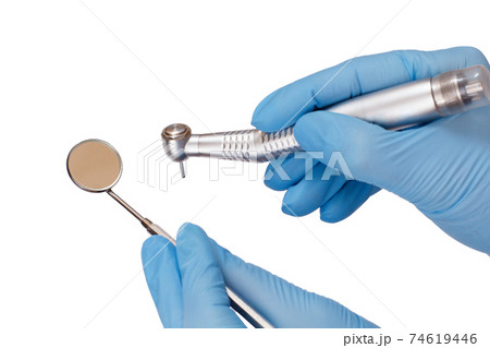 Dentist's hands in gloves with dental handpiece and mouth mirror. 74619446