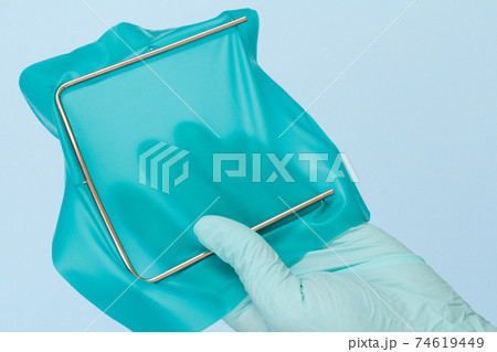 Dentist's hand in glove with dental cofferdam scarf and metal frame. 74619449