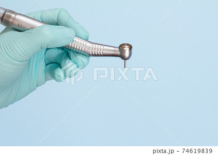 Dentist's hand in glove with dental handpiece. Dentist's hand in glove with dental handpiece. 74619839