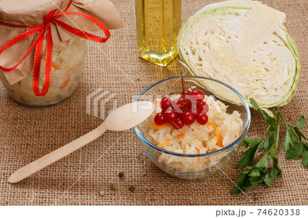 Fermented cabbage with herbs and spices in glass bowl and jar on the sackcloth. Fermented cabbage with herbs and spices in glass bowl and jar on the sackcloth. 74620338