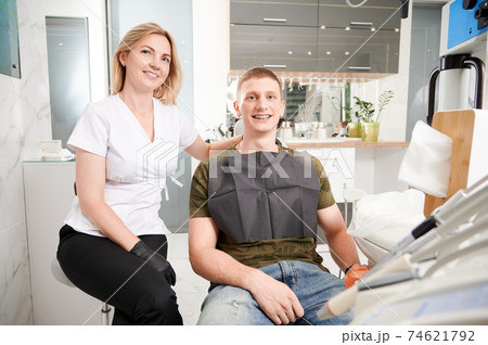Cheerful dentist and patient sitting in dental office. Cheerful dentist and patient sitting in dental office. 74621792
