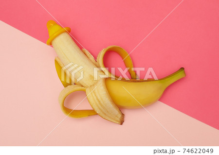 Banana with condom on two tone background Banana with condom on two tone background 74622049
