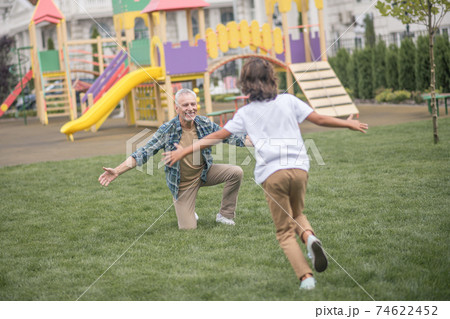 Boy running to his dads open arms and looking happy 74622452