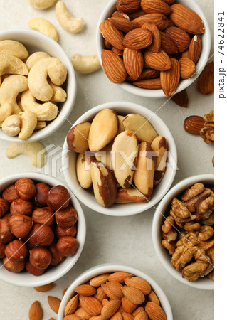 Bowls with different nuts on white textured background, top view 74622841