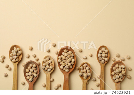 Wooden spoons with chickpea on beige background 74622921