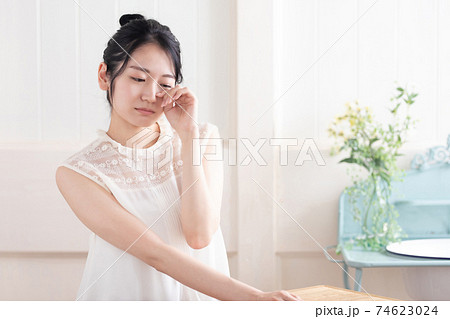 目をおさえる女性 74623024