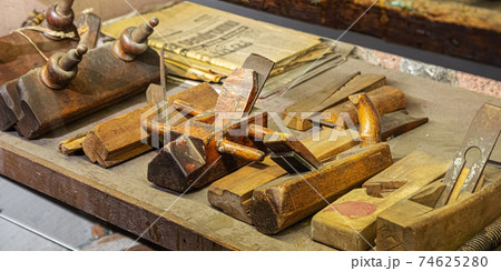 Old wooden and iron Planer for the manufacture of wooden planks. Old wood planer and spiral wood shavings, carpentry, woodworking and craftsmanship 74625280