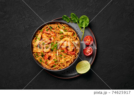 Mie Goreng in black bowl on dark slate table top. Indonesian cuisine prawn noodles vegetables dish 74625917