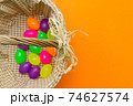 Wicker basket with colorful Easter eggs on yellow background.Copy space. 74627574