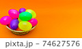 Wicker basket with colorful Easter eggs on yellow background.Panoramic 74627576