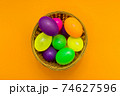 Wicker basket with colorful Easter eggs on yellow background.Top view. 74627596