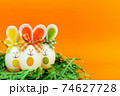 Three Easter eggs with bunny ears on nest spring yellow background. 74627728