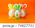 Three Easter eggs with bunny ears on spring yellow background. 74627731