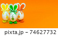 Three Easter eggs with bunny ears on spring yellow background. 74627732