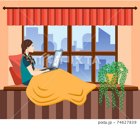 A woman works at a laptop while sitting on the windowsill at home. Freelance concept, quarantine due to covid-19. 74627839