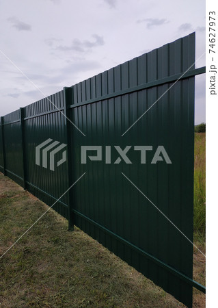 The worker with a screwdriver screws the screws into the fence, installing a metal fence. 74627973