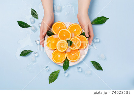 Natural healthy juicy organic orange slices and ice on blue background. Natural healthy juicy organic orange slices and ice on blue background. 74628585