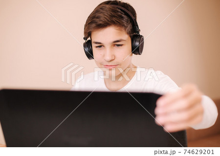 Young boy in wireless headphones open laptop and start playing games. Handsome teenage boy steamer 74629201