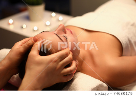 Woman is given rejuvenating facial massage in an aroma room 74630179