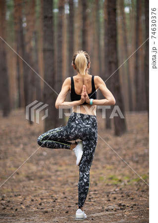Beautiful woman standing and doing yoga in forest. Exercise and 74630376
