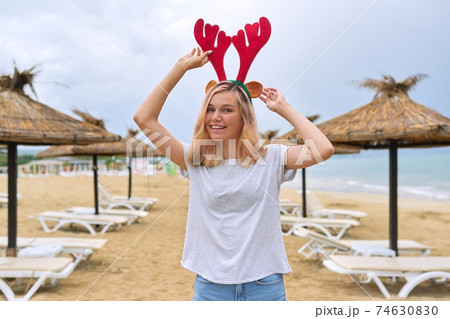 Beautiful young woman walking on the beach in Christmas deer ears 74630830