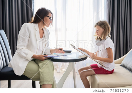 Child psychologist talking to girl kid in office Child psychologist talking to girl kid in office 74631279
