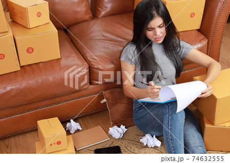 Young depress asian business woman in casual dress got headache from business failure from covid 19 with crumpled paper and online purchase shopping order box packaging (new normal concept) 74632555