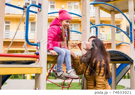 Mother with girl at playground. Woman holding she 74633021