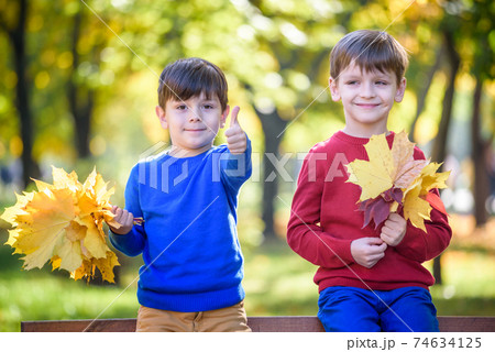 happy friends, schoolchildren having fun in autumn park among fallen leaves 74634125