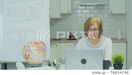 Senior female math teacher giving online lesson on laptop. Online distance learning education lesson concept. Senior female math teacher giving online lesson on laptop. Online distance learning education lesson concept. 74634248